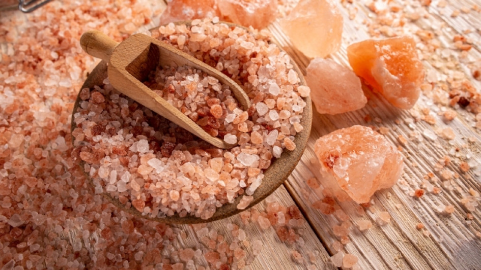 Mesa con sal rosa del Himalaya, un plato y una cuchara de madera.