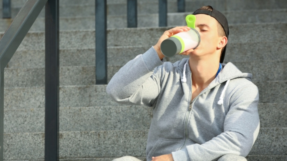 Hombre sentado en unas escaleras tomando proteina.