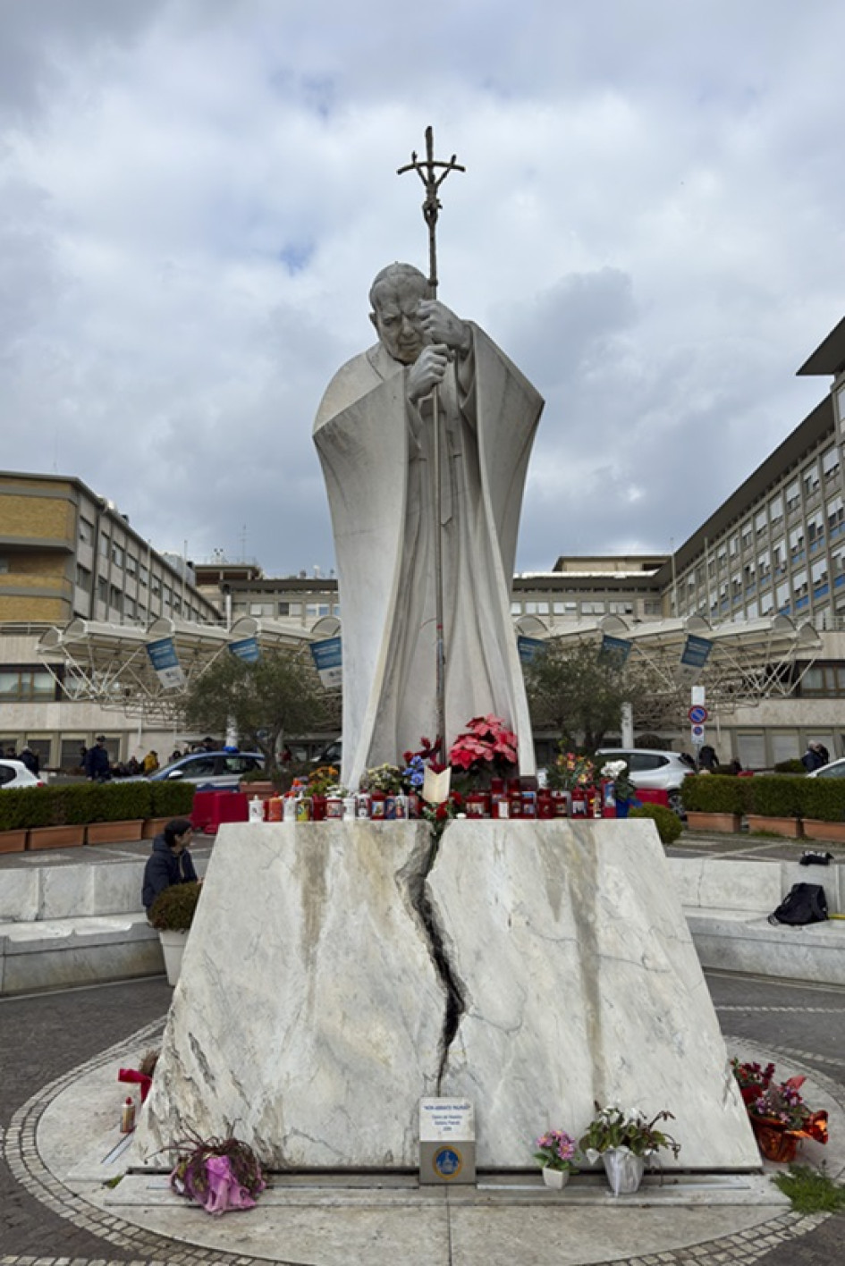 Velas y flores a los pies de la escultura de Juan Pablo II a las puertas del Hospital Gemelli de Roma donde permanece ingresado el papa Francisco.