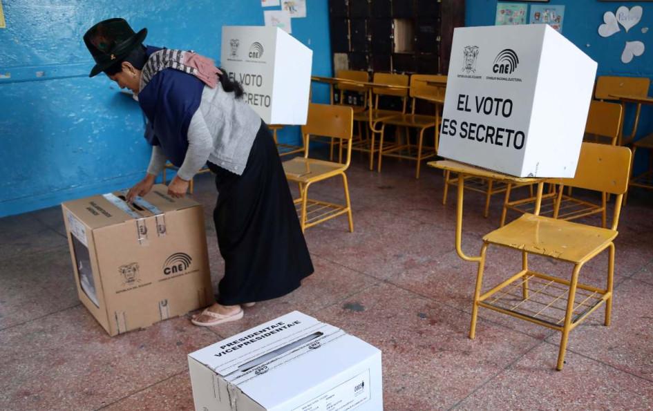 Una mujer introduce su voto en un puesto electoral en la Escuela 10 de Agosto durante las elecciones presidenciales y legislativas de Ecuador. 