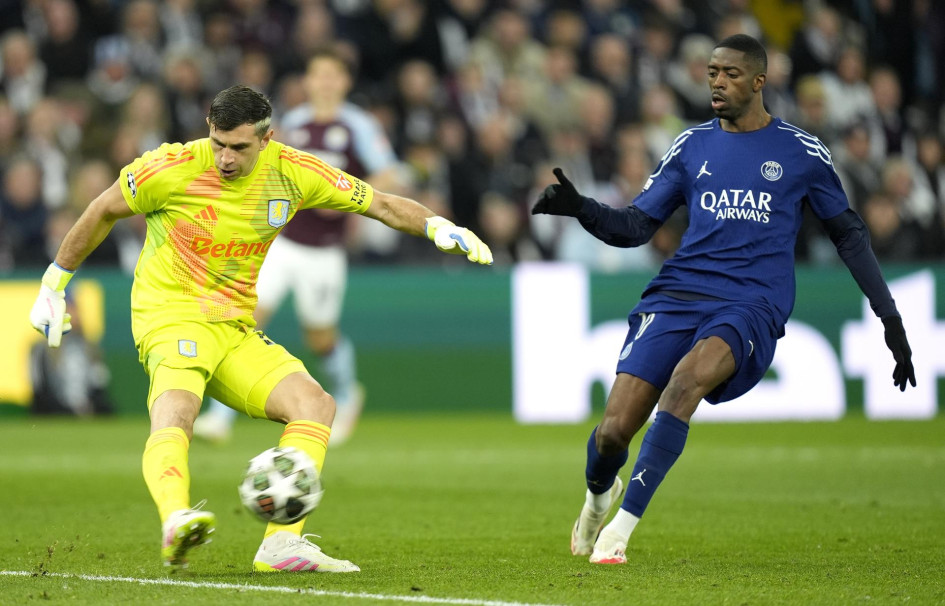 El portero Emiliano Martínez (izq.) del Villa juega el balón delante de Ousmane Dembele del PSG