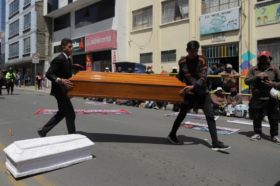 Personas mueven dos ataúdes vacíos en medio de una protesta de mineros este lunes en La Paz (Bolivia).