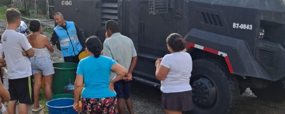 Con cocas y baldes la comunidad llega al carro de bomberos por agua.