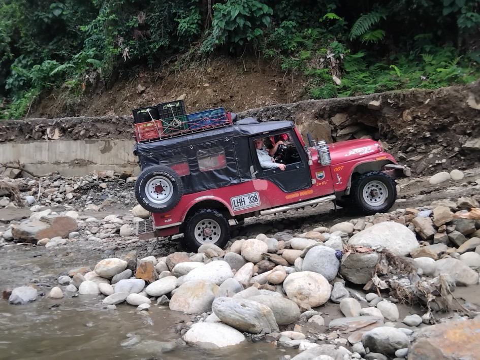Carros, chivas y motos se han visto cruzando un río entre Caldas y Antioquia para desplazarse entre dos municipios que se quedaron sin vía el 11 de abril, por una creciente del caudal.