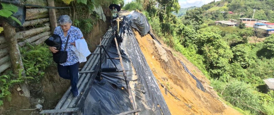 Dos mujeres cruzan por el puente artesanal que está sobre la vía colapsada de la vereda Java, de Manizales. 