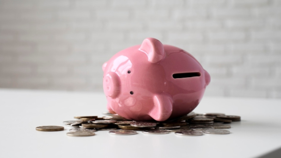 Alcancía en forma de cerdo encima de muchas monedas.