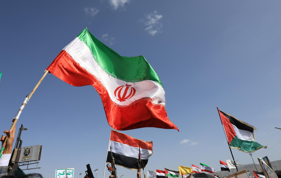 Partidarios hutíes ondean una bandera iraní (izq.) y las banderas del eje de resistencia respaldado por Irán durante una protesta contra Estados Unidos e Israel. 