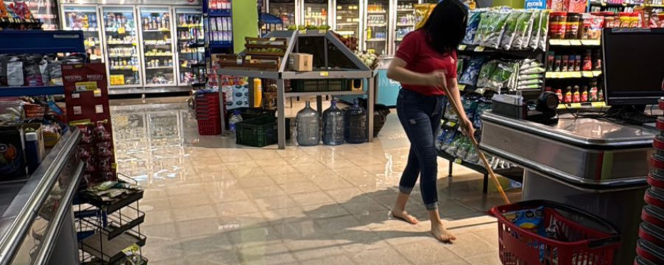 Este es un supermercado se inundó a raíz del daño de la tubería. Una empleada trapea el piso para retirar el agua. 