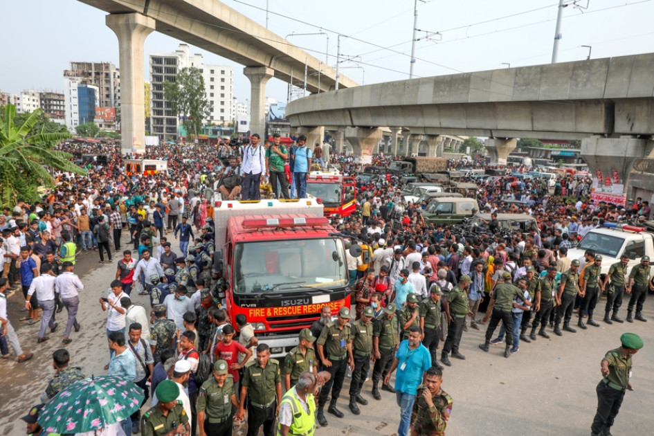 La gente se reúne cerca del lugar donde un avión de entrenamiento de la fuerza aérea se estrelló en el campus de Milestone College, en Dhaka, BangladeshLa gente se reúne cerca del lugar donde un avión de entrenamiento de la fuerza aérea se estrelló en el campus de Milestone College, en Dhaka, Bangladesh