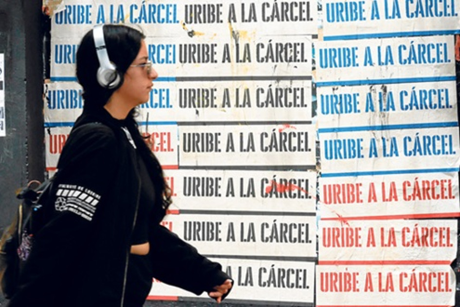 Una mujer camina frente a carteles en contra del expresidente de Colombia Álvaro Uribe, en Bogotá.