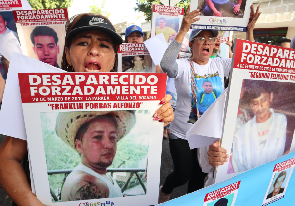 Familiares de víctimas de desaparición forzada protestan este sábado sosteniendo carteles con fotos de sus allegados desaparecidos, en Cúcuta (Colombia).