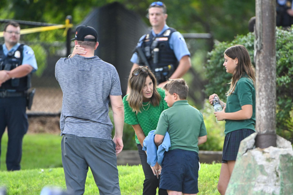 Un adulto y un niño se toman un momento mientras salen de la escuela mientras la policía responde a un tiroteo en una escuela católica en Minneapolis, Minnesota.