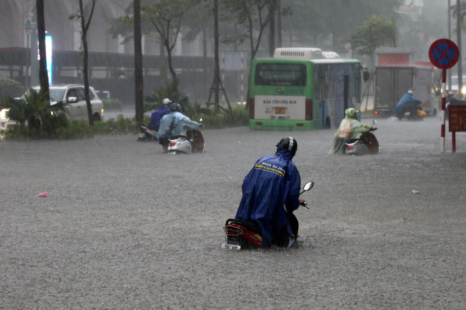 La gente se transporta con sus motos por una calle inundada en Hanoi (Vietnam).