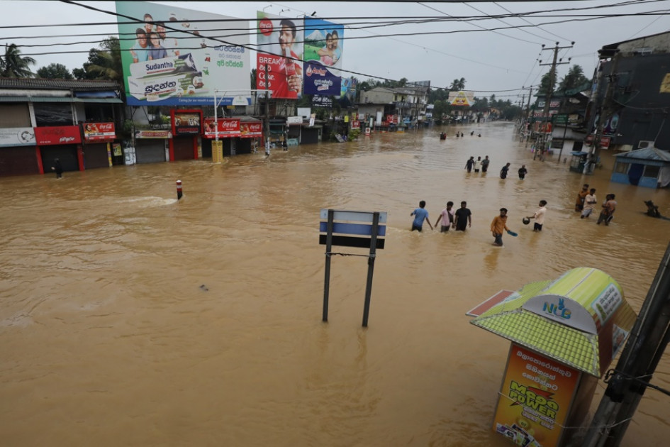 as víctimas de las inundaciones en Sri Lanka caminan por una carretera inundada durante las fuertes lluvias en un suburbio de Colombo