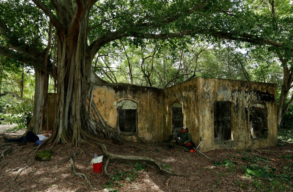 Foto del 5 de noviembre del 2025 que muestra personas sentadas cerca a una casa en ruinas, en Armero.