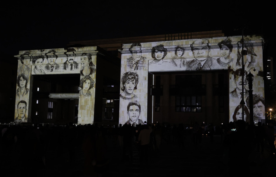 Fotografía donde se observa la proyección de rostros de víctimas sobre la fachada del Palacio de Justicia durante un homenaje este jueves, en Bogotá (Colombia).