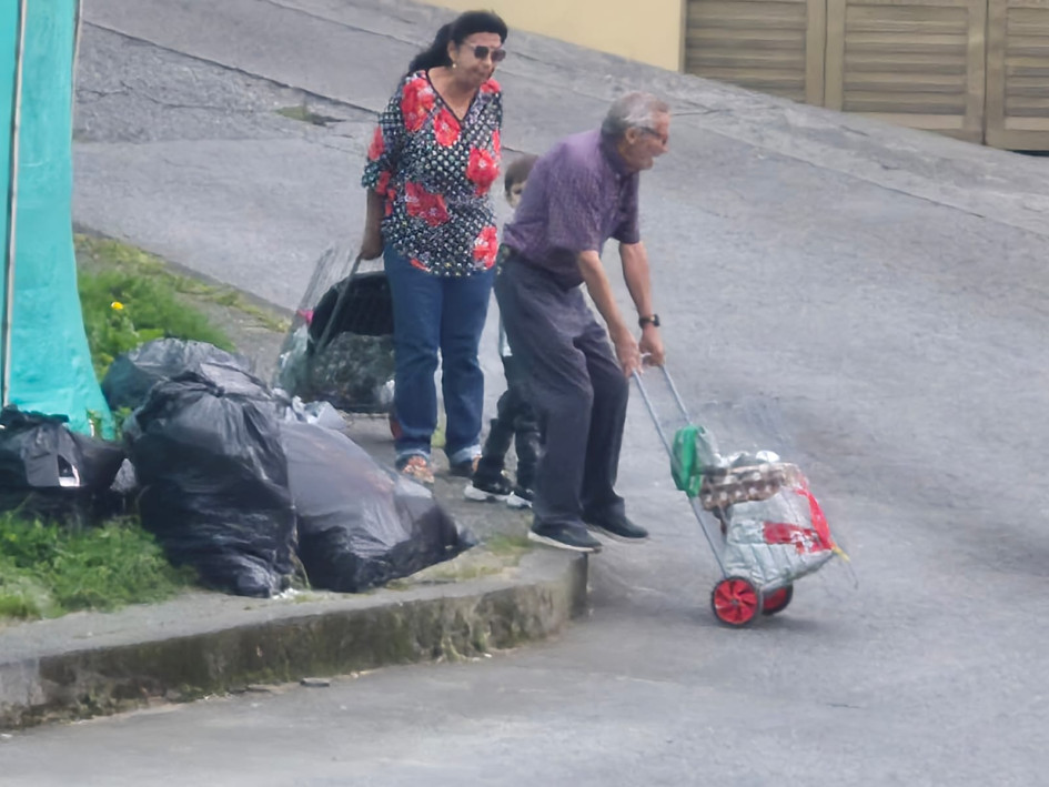 Dos adultos mayores con una niña tuvieron que bajar del anden para poder continuar con su camino debido a la basura que había en esa esquina.