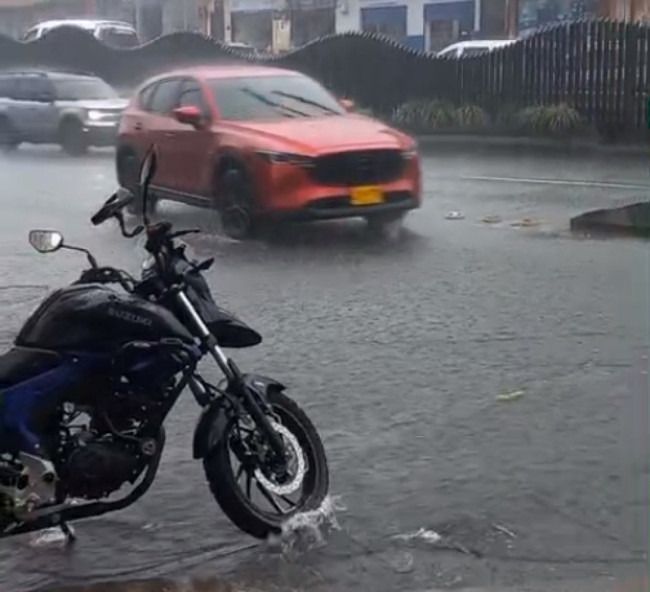 Un fuerte aguacero cayó en la tarde de este viernes en Manizales. En la foto, un carro pasa por encima de una tapa de alcantarilla que se levanta por la fuerza del agua en el sector de Los Agustinos.