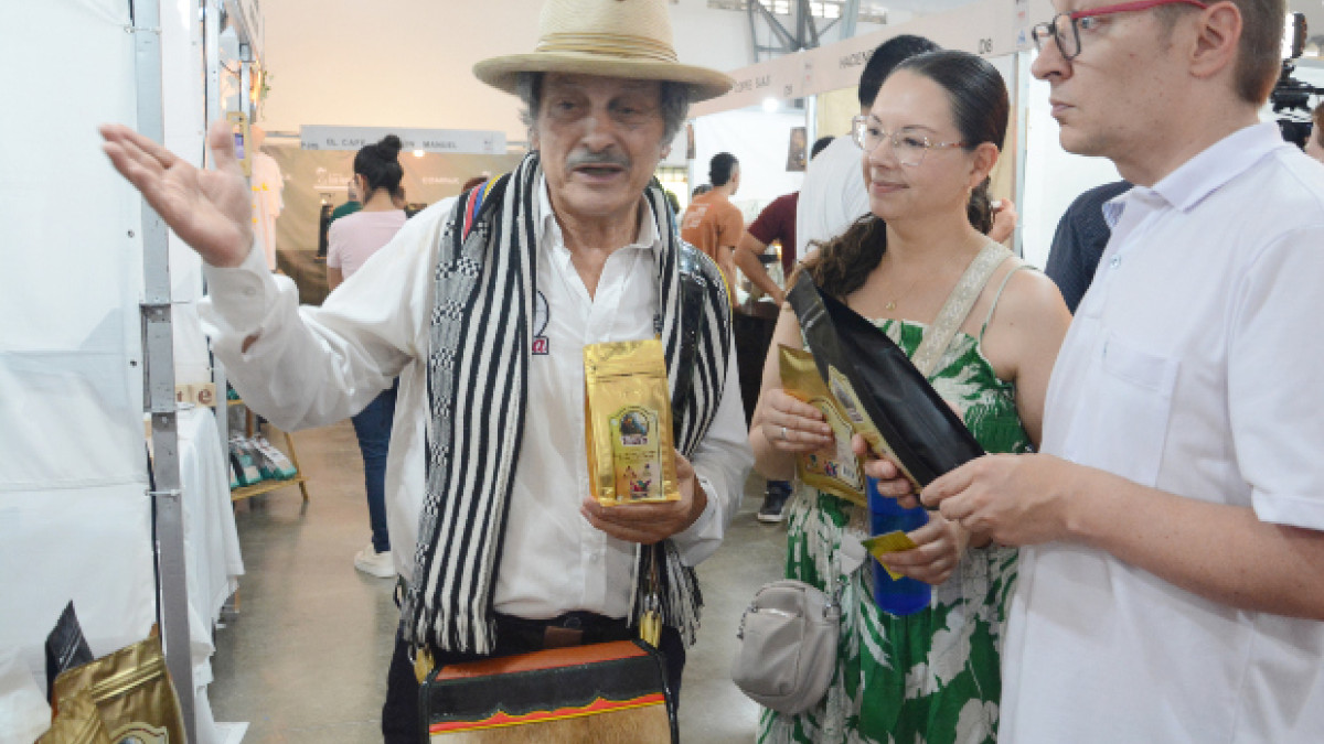 Jairo Elías Vásquez, de la vereda Guacas de Manizales, expone su producto especial Café Vasca, en Café Fest 2026. Felipe Botero y Andrea Sánchez llegaron al estand que el señor atiende con su hijo Jacobo Vásquez.